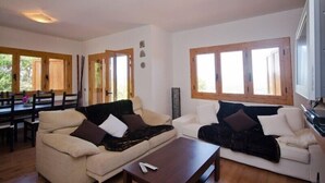 Amplia sala de estar con dos sofás, una mesa de centro y ventanas grandes.
