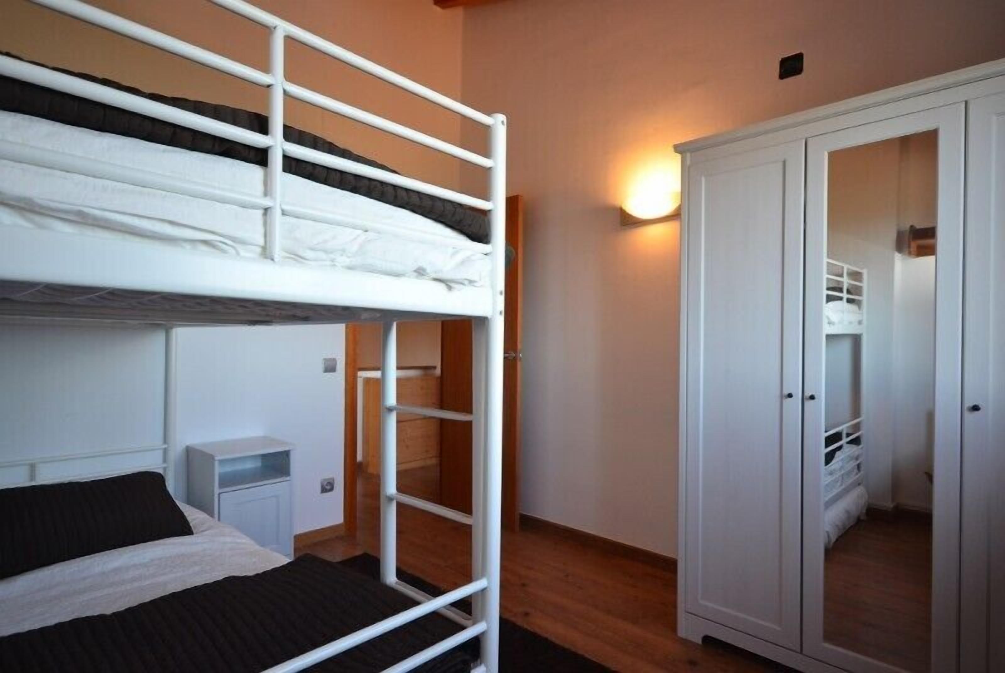 A bunk bed room with a wardrobe and a bedside table.