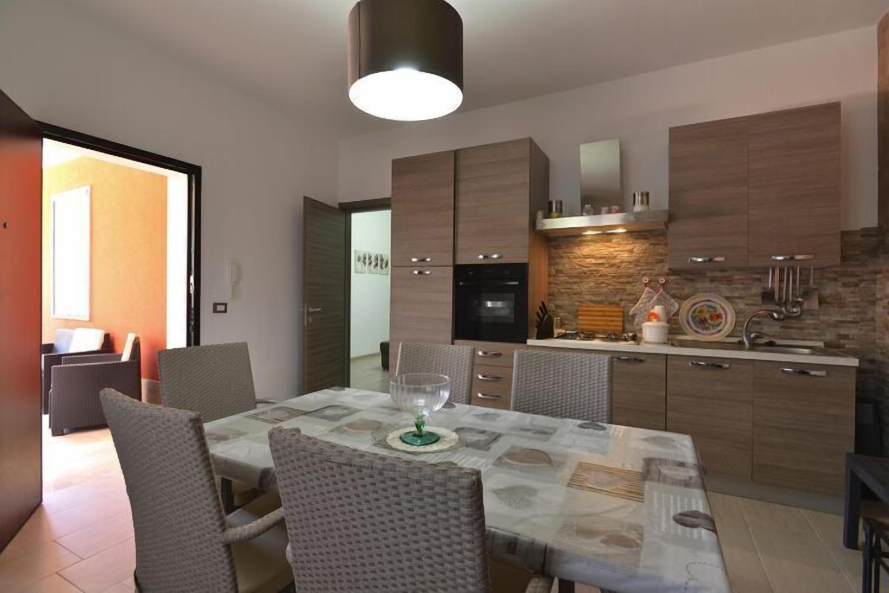 A modern kitchen with wooden cabinets, a built-in oven, and a stone backsplash.