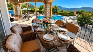 A covered outdoor dining area with wicker furniture, a pool, and mountain views. - Stunning Villa Semira, Perfect Condition, Private Pool & 1000m2 Garden,WIFI (Muğla)