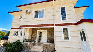 A two-story house with a stone facade, a front porch, and a clear sky. - Stunning Villa Semira, Perfect Condition, Private Pool & 1000m2 Garden,WIFI (Muğla)