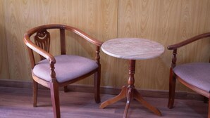A wooden chair with a cushioned seat and a small round table with a woven top.