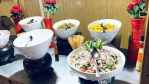 A buffet table with various dishes, including pasta, salads, and a large bowl of mixed vegetables.