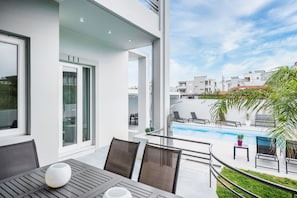 A modern outdoor patio with a pool, seating area, and a view of the surrounding neighborhood.