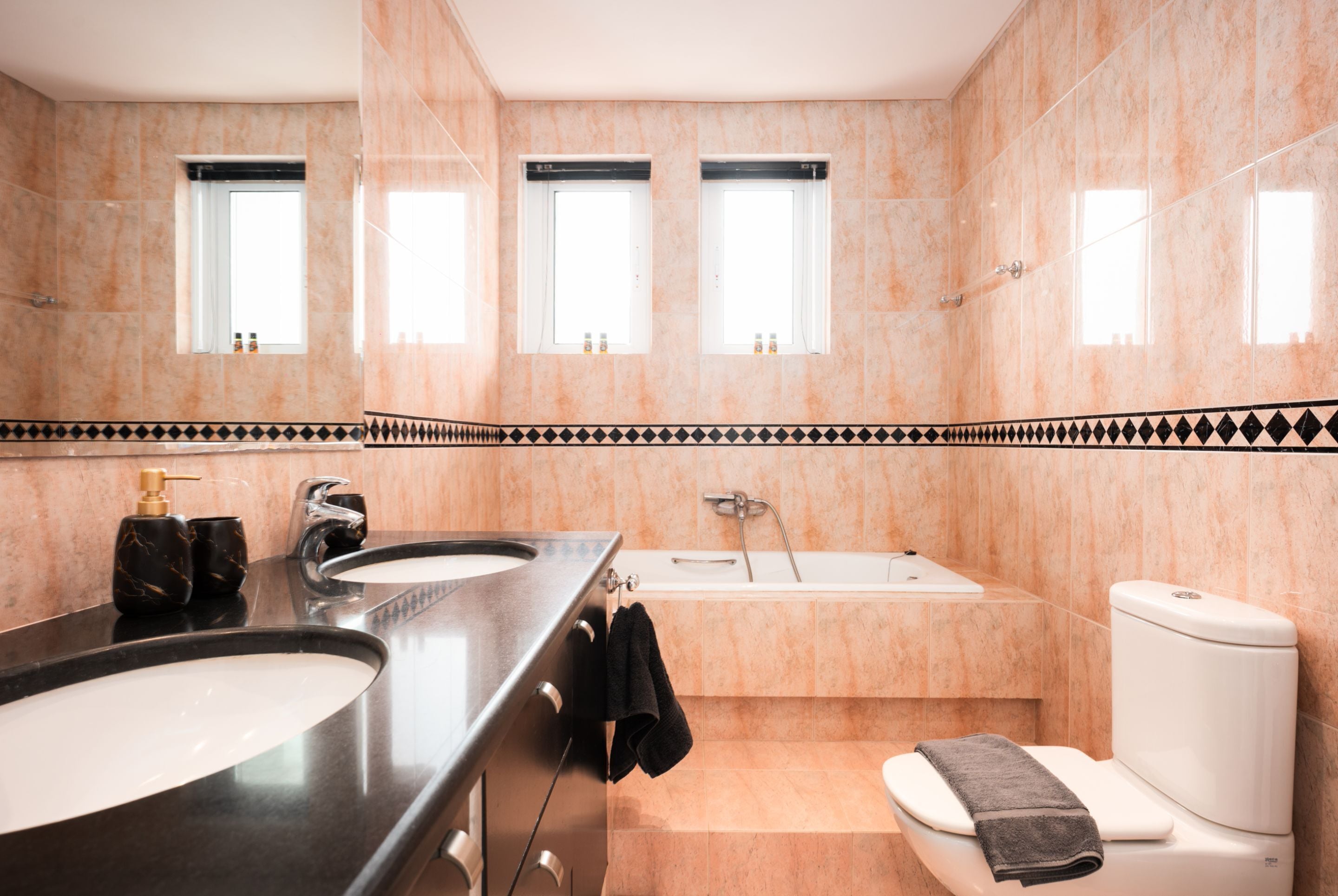 A modern bathroom with two sinks, a bathtub, and a toilet.