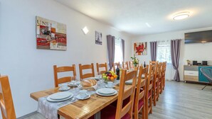 A dining area with a long wooden table set for multiple people, surrounded by chairs. - Pool & Sauna Countryside Retreat Klara (Velika Gorica)