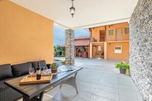 A covered patio area with a table, chairs, and a bottle of wine. - Pool House Klara With Sauna (Velika Gorica)