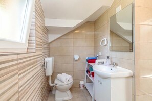 Een badkamer met toilet, wastafel en spiegel.