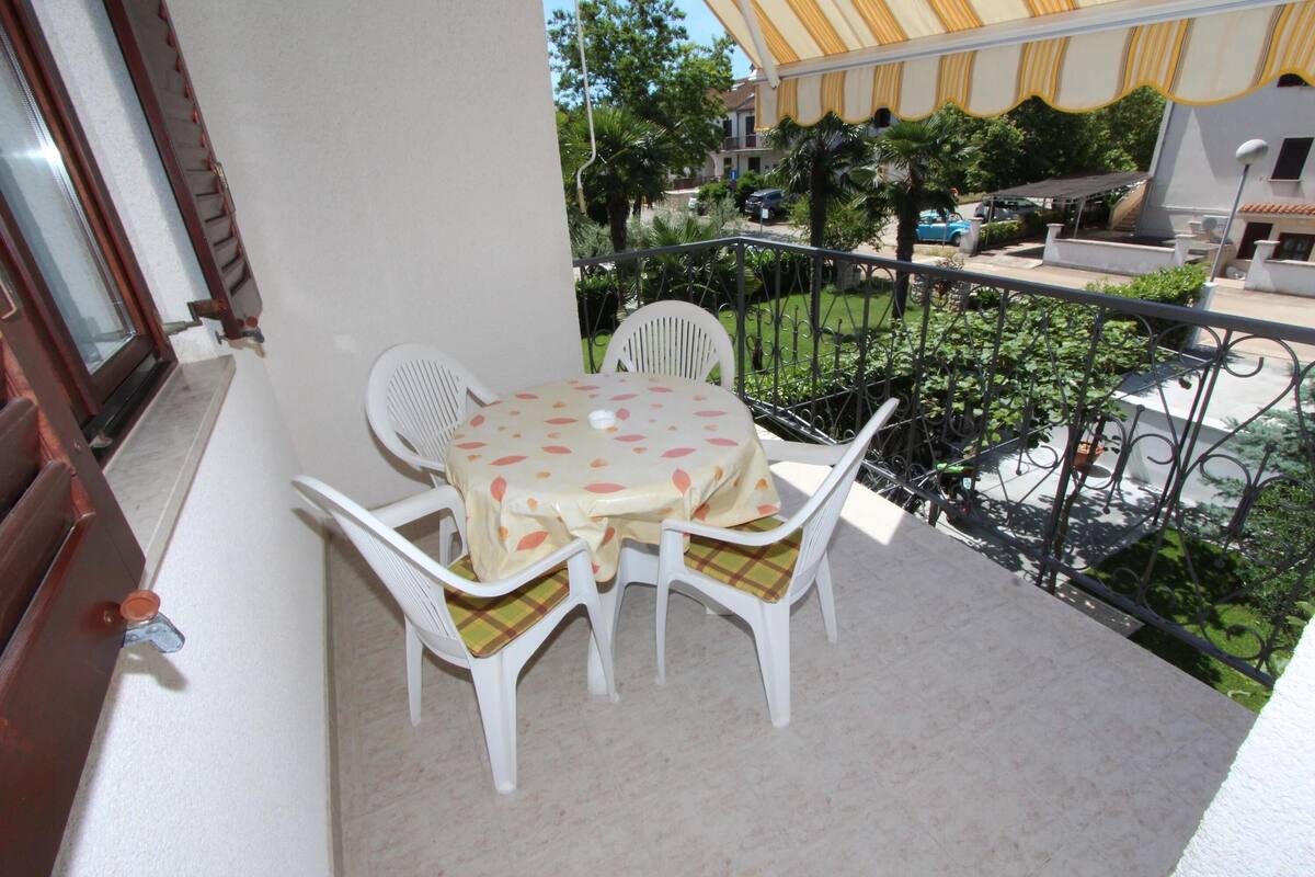 A balcony with a table and chairs, a railing, and a view of the surrounding area.