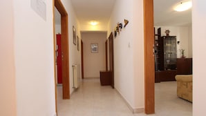 A hallway with a tiled floor, wooden door frames, and a red door on the left. - Apartments Denise (Rovinj)