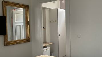 A bedroom with a bed, a chandelier, a mirror, and a wardrobe.