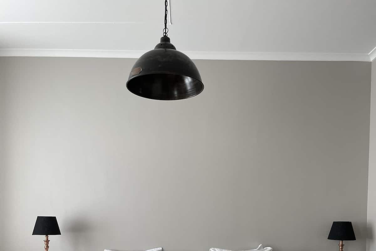 A bedroom with a large bed, two bedside tables with lamps, and a hanging light fixture.