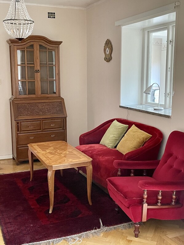 Una sala de estar con un aparador de madera, un sofá rojo, una mesa de centro de madera y un sillón rojo.