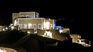 Un edificio a più piani con finestre illuminate e una sezione illuminata di blu, probabilmente un hotel o un complesso residenziale.