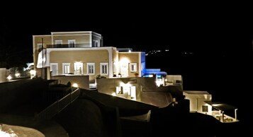 Un edificio de varios pisos con ventanas iluminadas y una sección iluminada en azul, probablemente un hotel o complejo residencial.