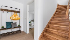 Eine Treppe mit Holzbodenstufen und einem Metallgeländer, die zu einem Raum mit einem Bett und einem Nachttisch führt.
