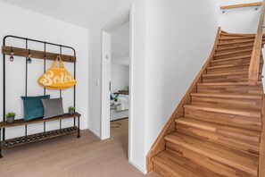 Eine Treppe mit Holzbodenstufen und einem Metallgeländer, die zu einem Raum mit einem Bett und einem Nachttisch führt.