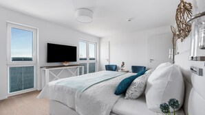 Ein modernes Schlafzimmer mit Bett, Fernseher und Schreibtisch.