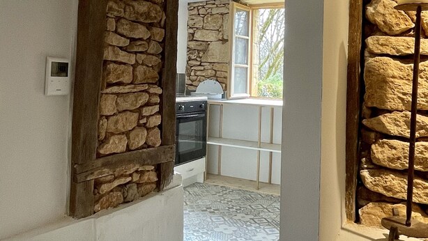 Una cocina con paredes de piedra, un ventanal y vistas al exterior.
