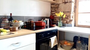 Una cocina con pared de piedra, encimera de madera y diversos utensilios.