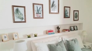 Une chambre à coucher comprenant un lit, des oreillers, une table de chevet, une lampe et des étagères murales ornées de tableaux et de livres.