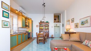A compact living space with a kitchen, dining area, and a sofa. - Terrazza Morgera by Napoliapartments (Casamicciola Terme)