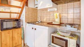 Una cocina compacta con horno integrado, cafetera y microondas.