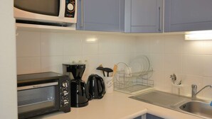 A kitchen with a microwave, toaster, coffee maker, and a dish rack.