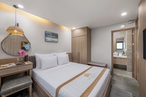 Una habitación de hotel moderna con cama, mesita de noche, lámpara, una obra de arte y un armario.