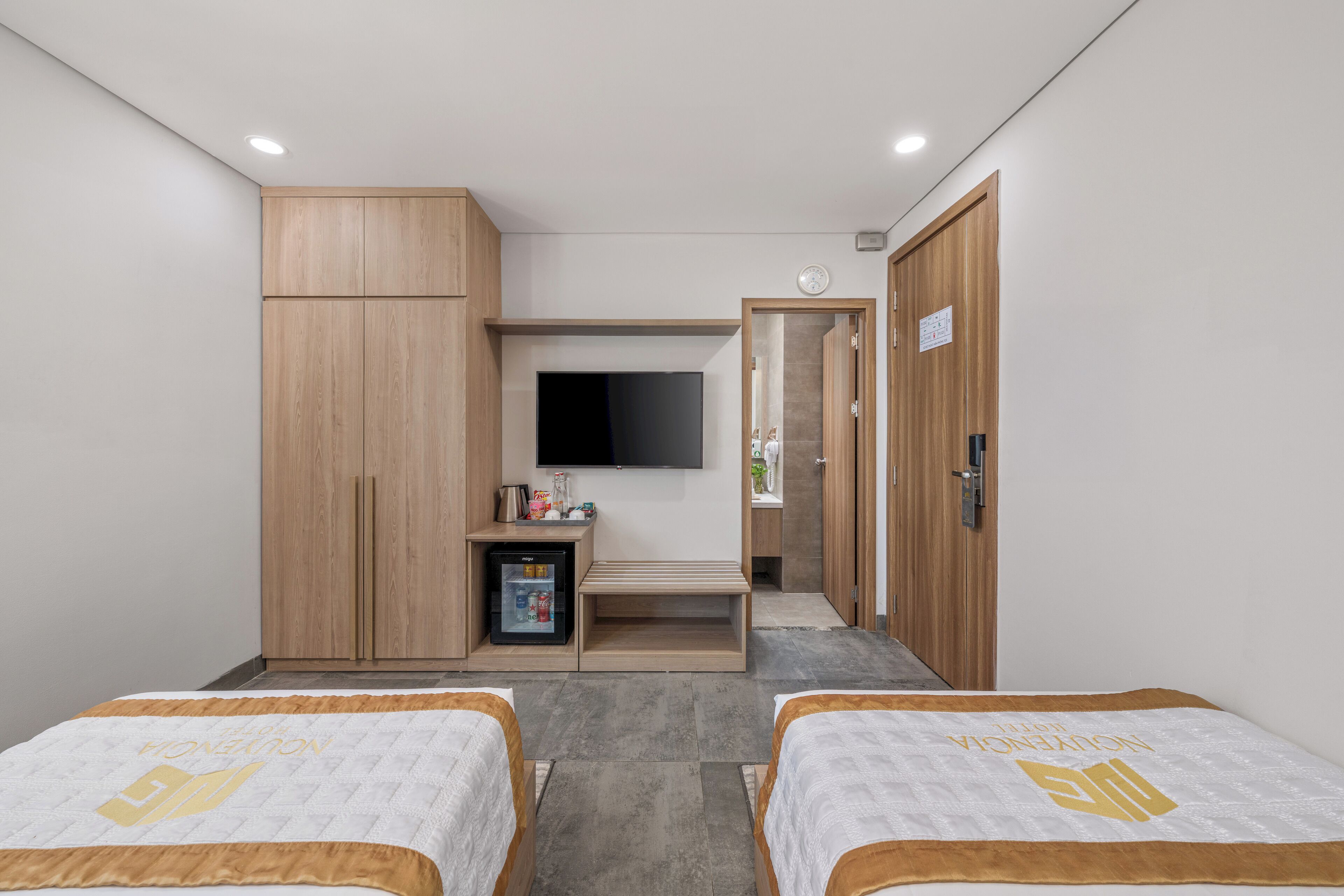 A hotel room with two beds, a television, a minibar, and a wardrobe.