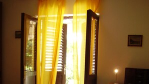 A bedroom with a bed, a chair, a desk with a lamp, and a window with curtains. - Apartment 1, located 200 meters from the sea in character house.  (Rovinj Borik)