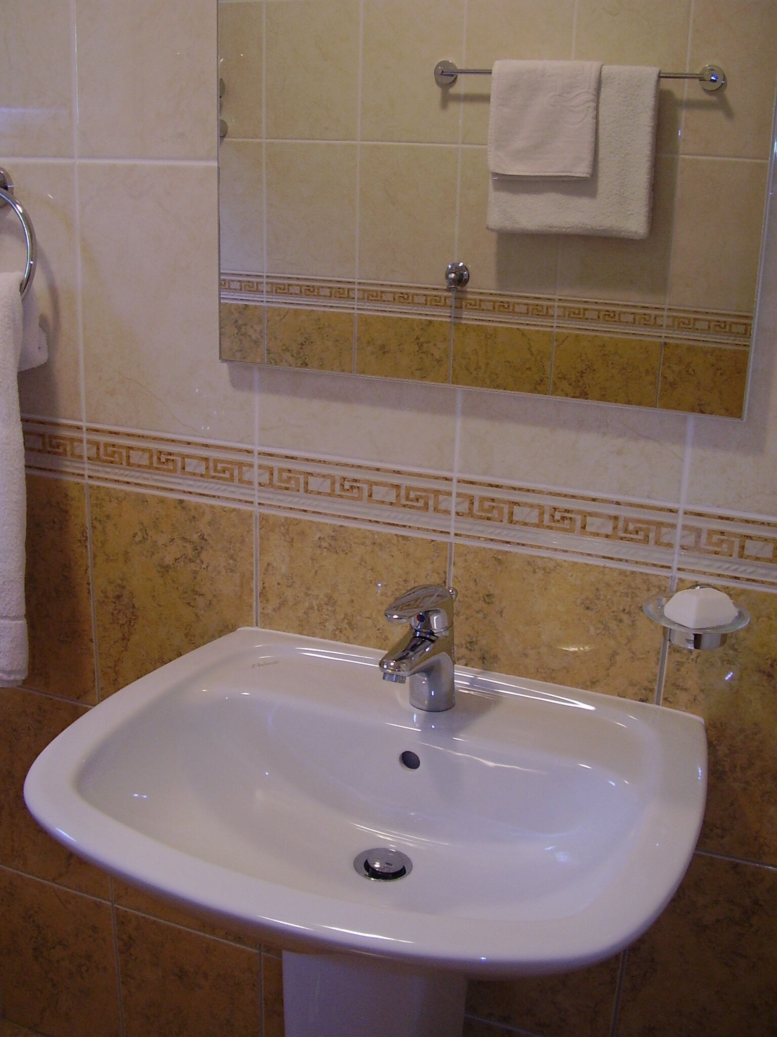 A bathroom with a white sink, a mirror, and a towel rack.