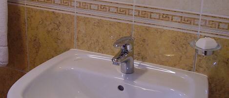 A bathroom with a white sink, a mirror, and a towel rack.