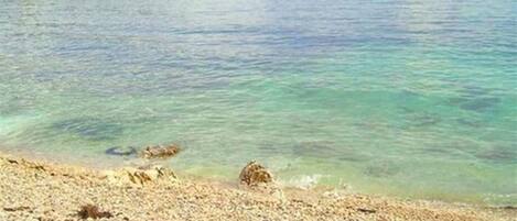 A beach with clear water and a distant island.