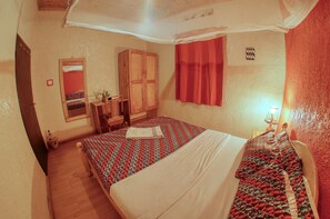 A bedroom with a bed, a wardrobe, a mirror, and a window with curtains. - Tea House BnB Apartment (Kigali)