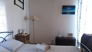 A bedroom with two beds, a nightstand, a lamp, a painting, and a view of the outdoors. - STUDIO APARTMENT WITH GARDEN VIEW (Scicli)