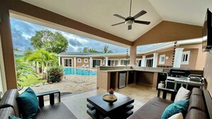 A spacious living area with a pool, outdoor kitchen, and a view of a residential building.