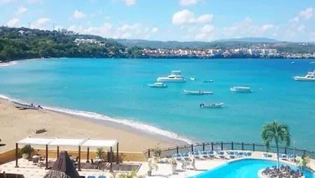 A resort with a pool, beach, and boats in the water.