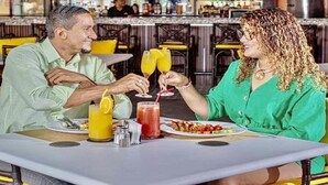 A couple seated at a table in a restaurant with a bar in the background.