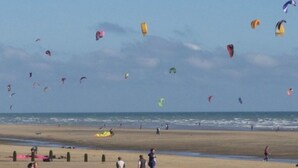 Una playa con gente y cometas.