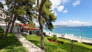 A coastal walkway with a stone path, trees, and a view of the sea. - Hotel Val  (Seget)