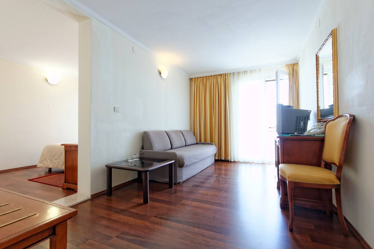 A living room with a sofa, a coffee table, a wooden chair, and a television.