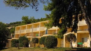 A multi-story building with balconies, surrounded by trees and greenery.