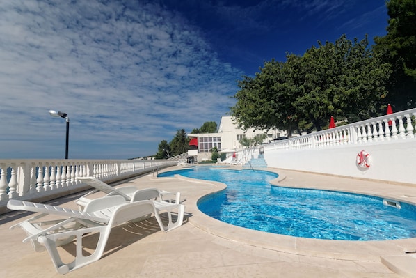Una piscina al aire libre de temporada, sombrillas