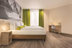 A hotel room with a bed, a desk, a chair, and a large wall mural. - Super 8 by Wyndham Chemnitz (Chemnitz)