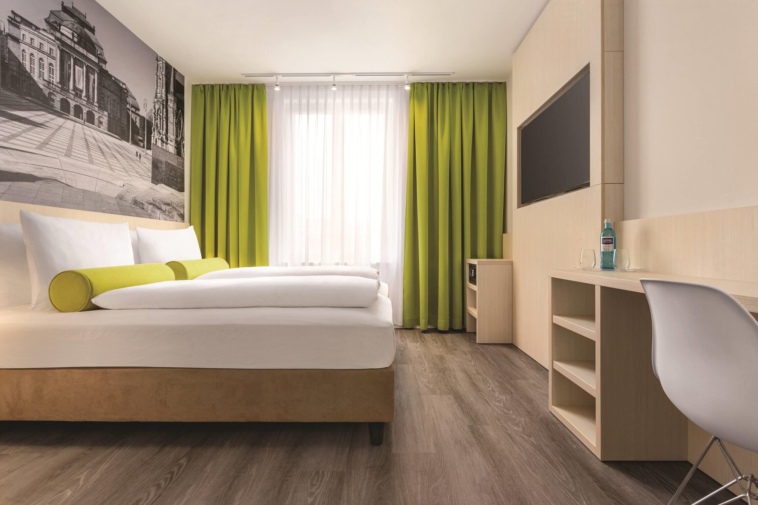Una habitación de hotel con cama, escritorio, silla y televisión.