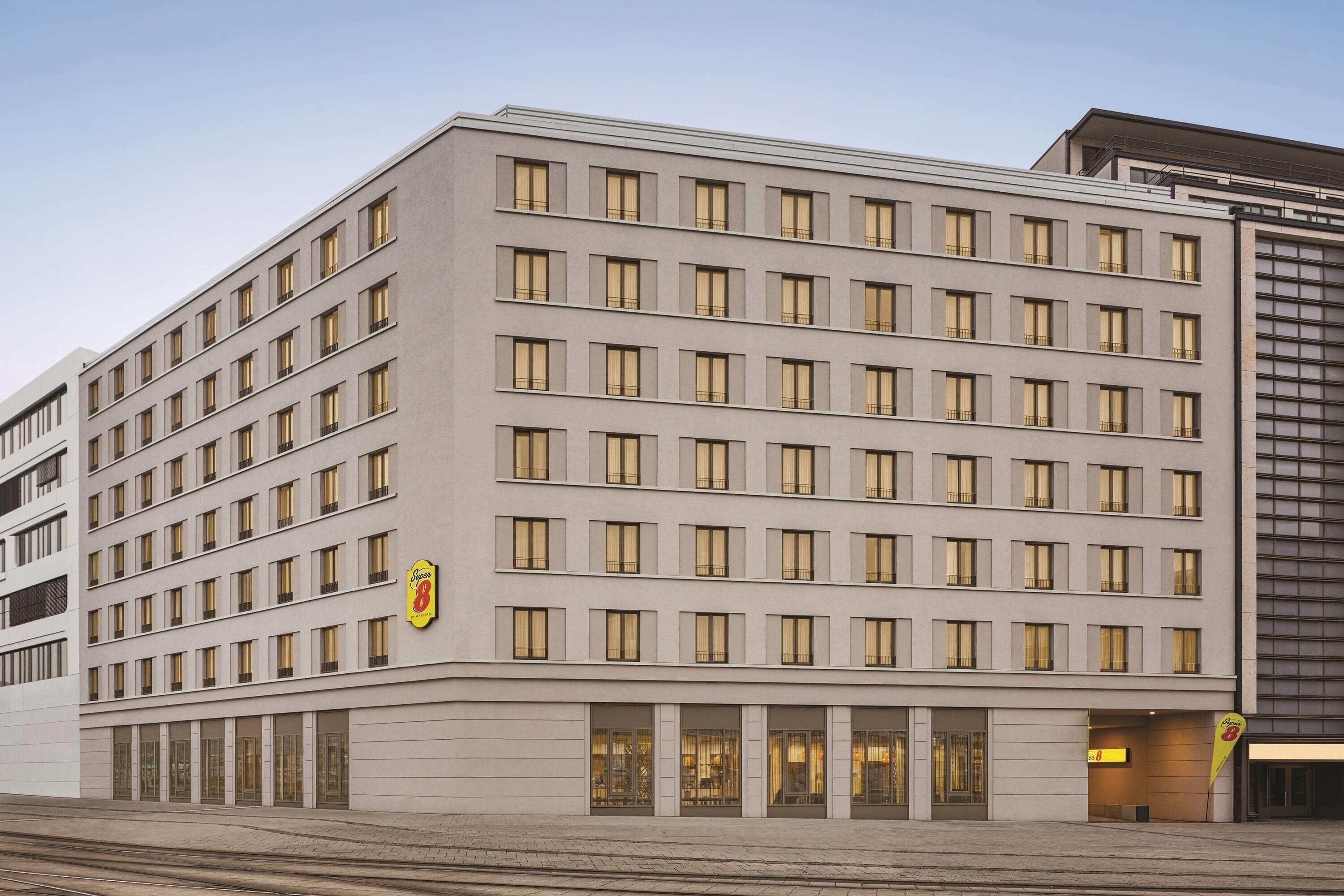 Um hotel com vários andares, fachada uniforme, várias janelas e um logotipo chamativo na lateral.