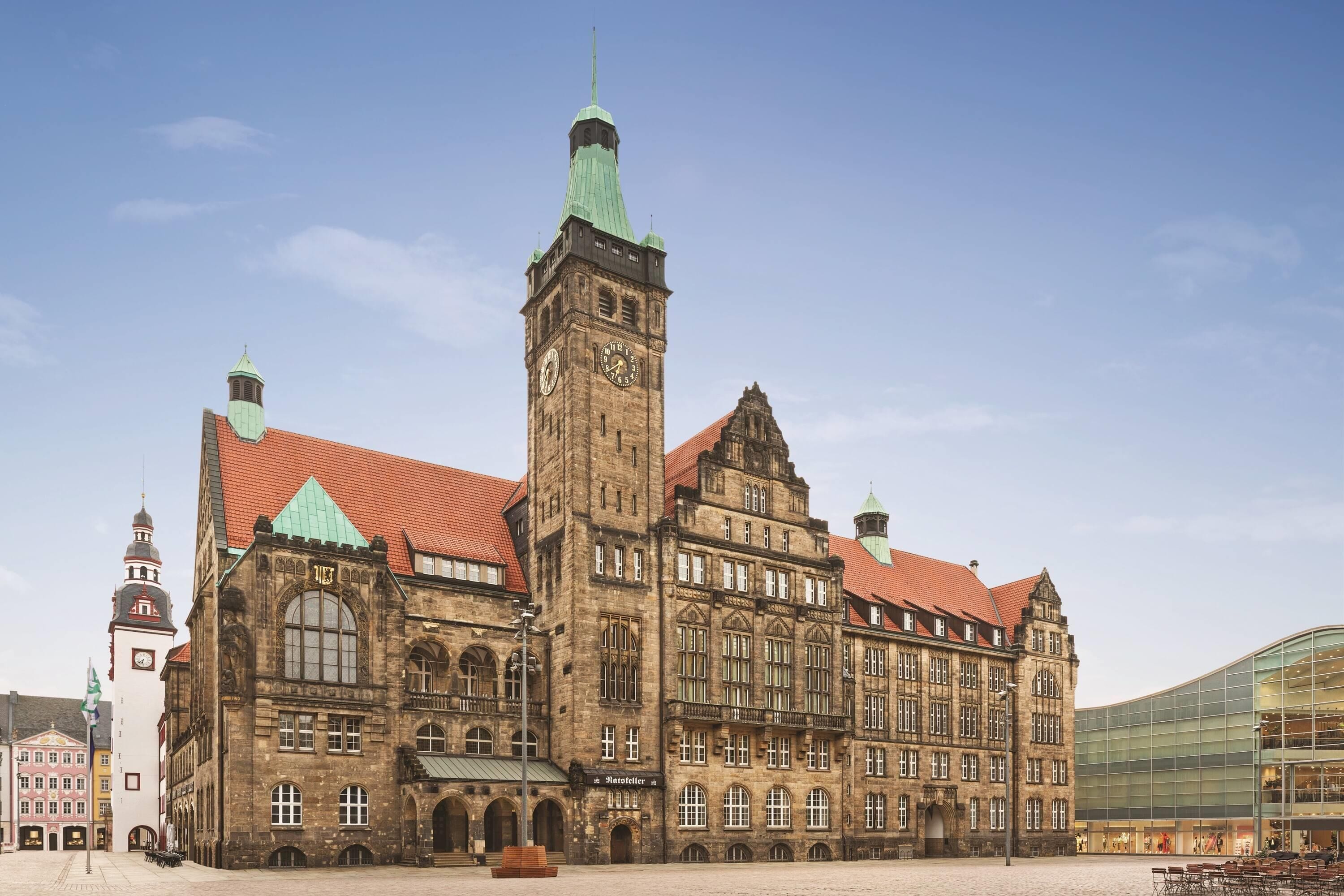 A historic building with a prominent clock tower, arched windows, and a red-tiled roof.