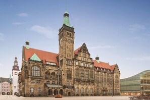 A historic building with a prominent clock tower, arched windows, and a red-tiled roof. - Super 8 by Wyndham Chemnitz (Chemnitz)