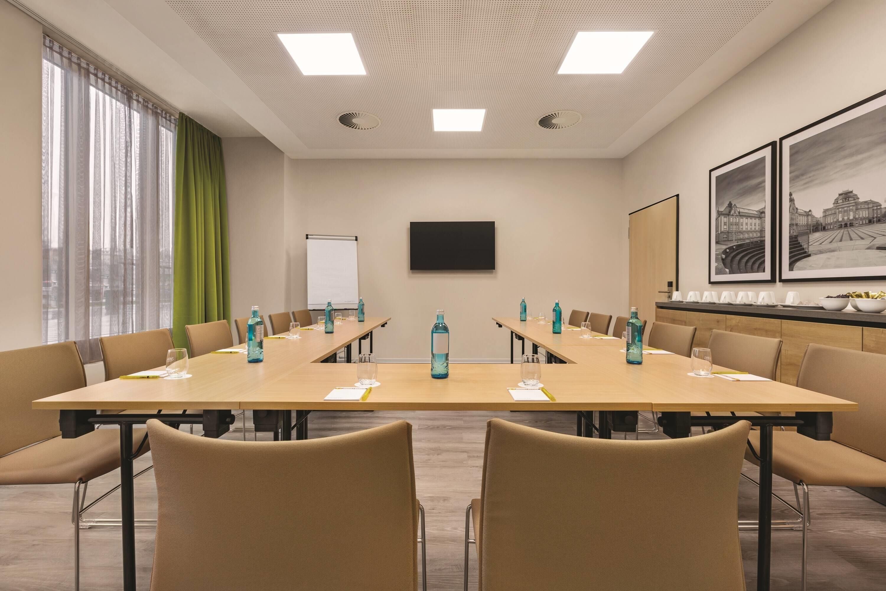 Un salón de conferencias con una larga mesa, sillas, una pizarra y cuadros en la pared.